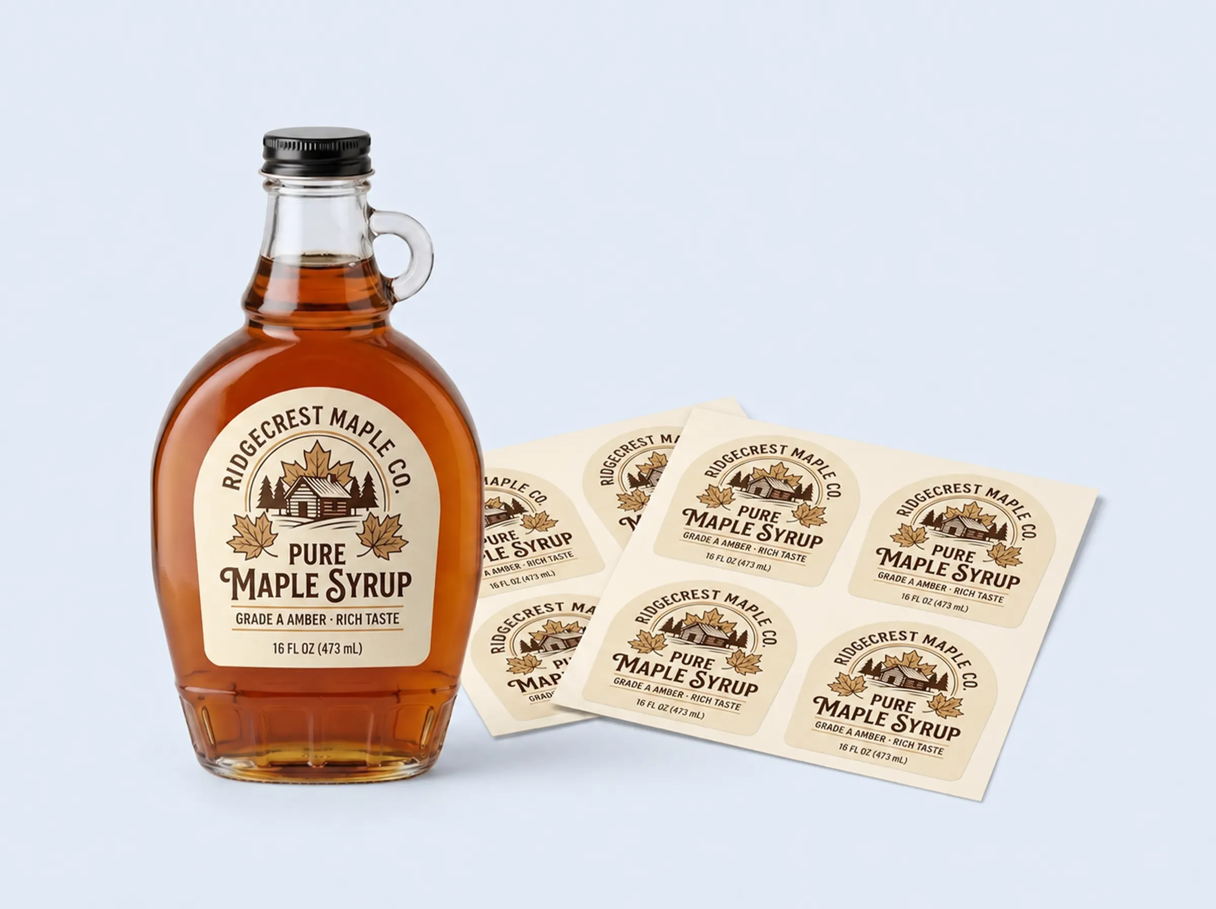 A glass maple syrup bottle displayed next to sheets of custom die-cut labels with a rustic design.
